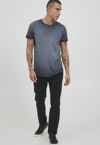 Marineblå gradient t-skjorte med korte ermer, rund hals og myk tekstur, kombinert med mørke slim-fit bukser og svarte joggesko.