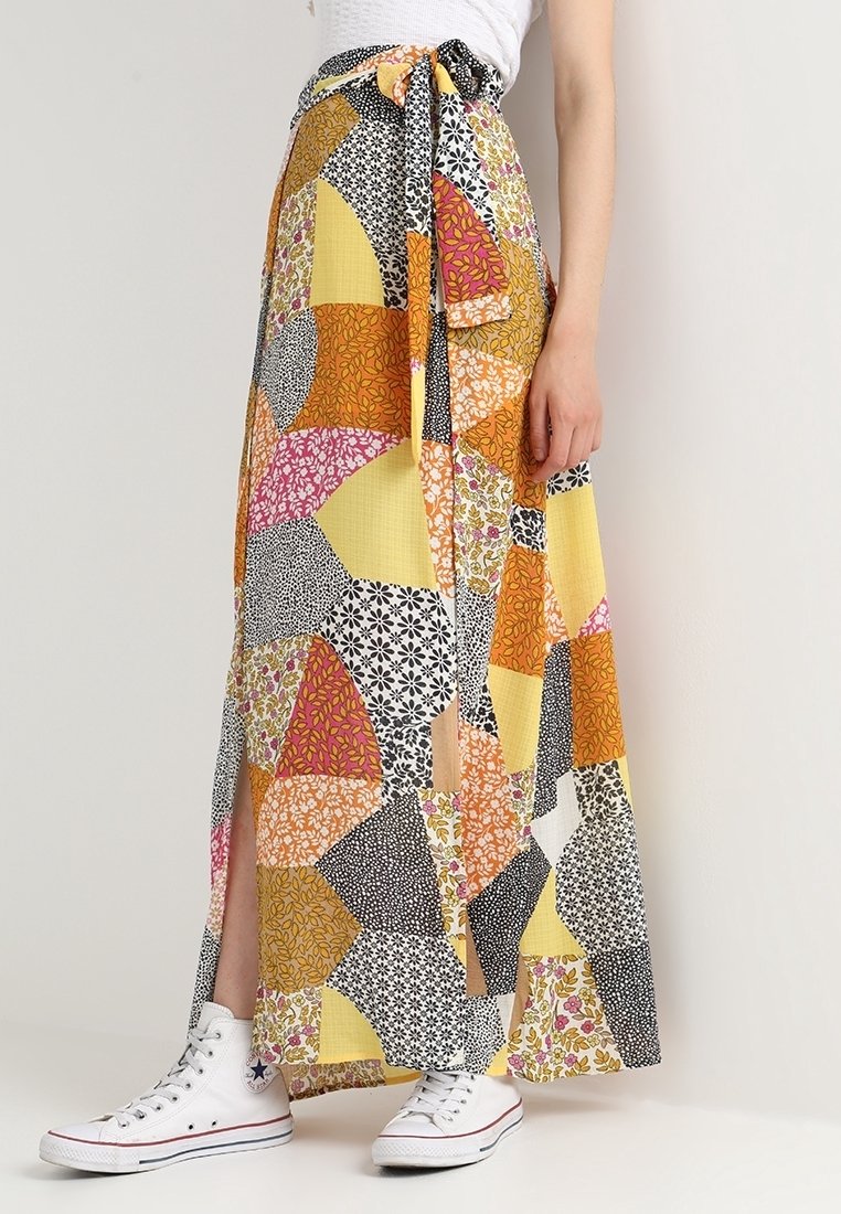 Lunga gonna in patchwork con vari modelli floreali e geometrici in giallo, nero, rosa e arancione. Vita con lacci, presenti fessure laterali.