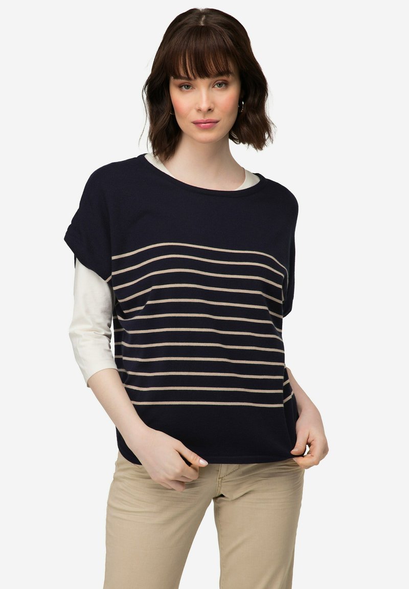Námořnická modrá pletená halenka s béžovými vodorovnými pruhy, krátkými rukávy a širokým výstřihem. Nositá přes bílou košili s dlouhým rukávem. Volný střih.