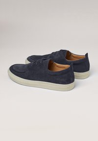 Scarpe in suede blu navy con punta rotonda, texture liscia, suola in gomma beige e design minimal dei lacci. Presentano un logo discreto sul tallone.