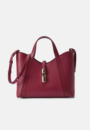 Sac à main en cuir bordeaux avec des poignées doubles, une bandoulière amovible et un fermoir doré. Finition texturée avec des accents de design géométrique.