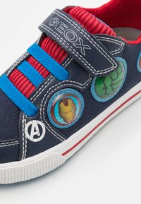 Sneaker della marina con elastico rosso e cinturini blu, caratterizzato da design circolari di personaggi Marvel. Suola bianca accentuata da striscia rossa.