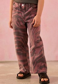 Rosa und graue Zebra-Print-Culottes mit Vordertaschen und Knopfverschluss, kombiniert mit schwarzen Riemchensandalen.