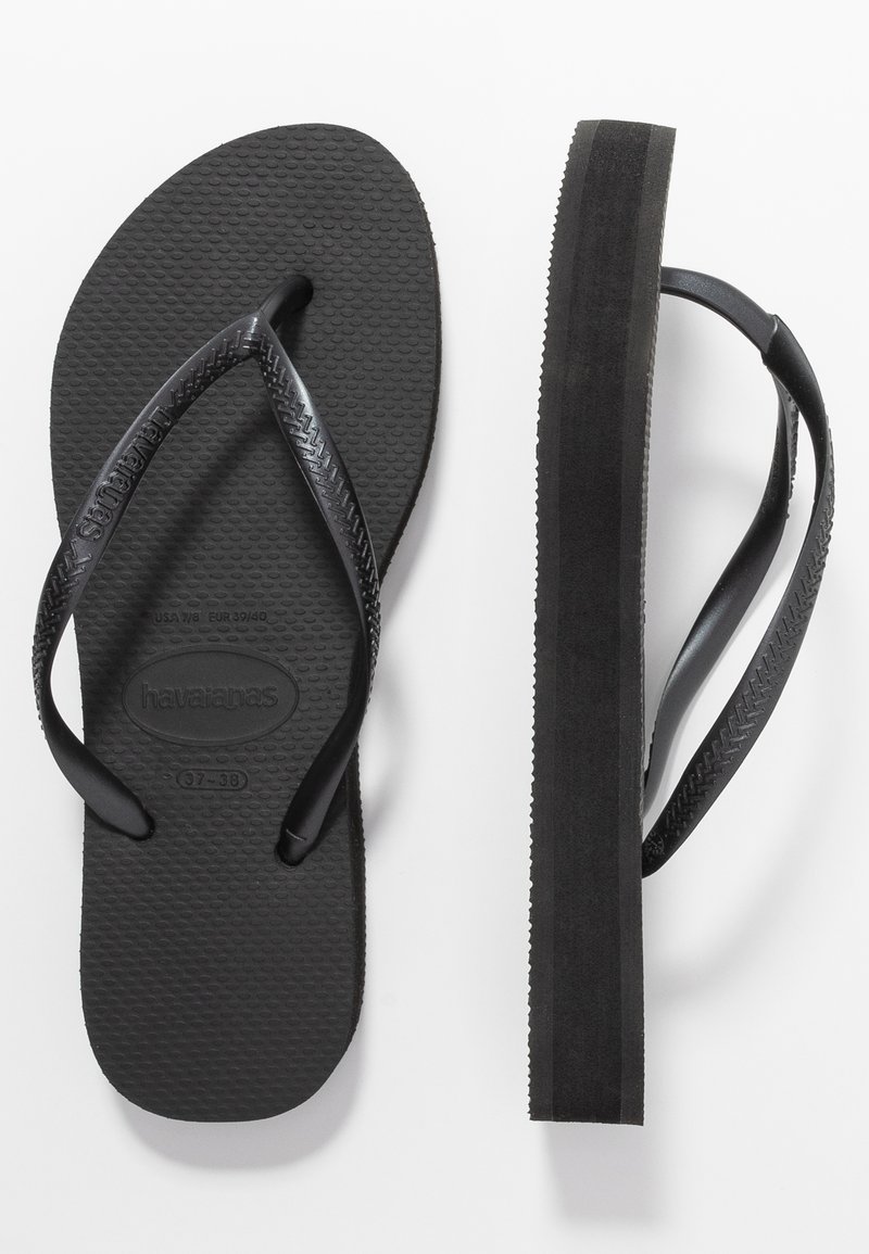 Juodos flip-flop šlepetės su tekstūruotais guminiais padais ir plokščiomis dirželiais, su prekės ženklu ant pado ir lygiu juodu išoriniu padais.
