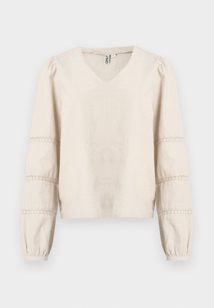 Blusa beige claro con escote en V, mangas largas abullonadas y detalles de encaje alrededor de los puños. Hecha de tela suave y texturizada.