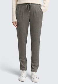 Grijze en zwarte geblokte broek met een elastische tailleband met trekkoord, zijzakken en taps toelopende pijpen, gecombineerd met witte sneakers.