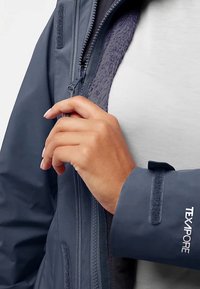 Marineblaue wasserabweisende Jacke mit weichem Fleecefutter, strukturiertem Stoff, durchgehendem Reißverschluss und Klettverschluss an den Bündchen; mit "TEXAPORE"-Markenaufdruck.