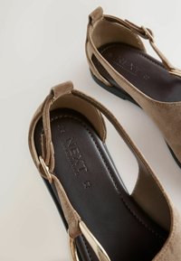 Sandales slingback en daim beige avec semelles intérieures noires matelassées et boucles dorées, avec la marque « NEXT » embossée sur la semelle intérieure.