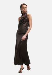 Top halter in satin nudo con scollo drappeggiato, abbinato a una gonna lunga fino al pavimento dello stesso tessuto. Texture liscia, colore marrone scuro e design minimalista.