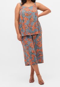 Grå blommig topp och culottbyxor med röda och orange blommönster. Mjuk tyg med avslappnad passform och tunna axelremmar. Remsandaler i brunt.