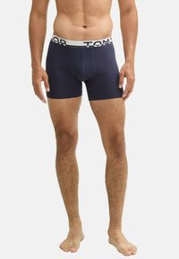 Caleçons boxers en coton bleu marine avec une taille élastique arborant un logo blanc. Texture lisse, design ajusté, longueur mi-cuisse.