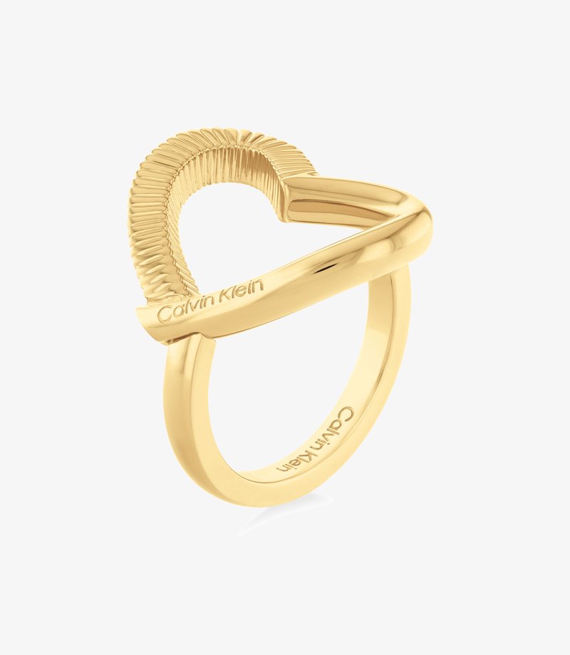 Goldfarbener Ring mit einer geschwungenen Form, gerillter Textur und glattem Band. Auf der Innenseite eingraviert "Calvin Klein".