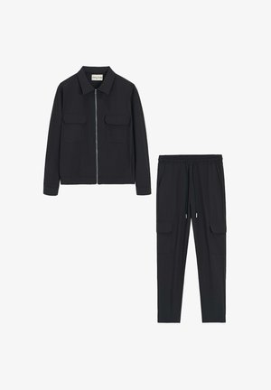 Veste noire zippée avec deux poches avant et un pantalon de jogging noir assorti, avec des poches latérales et une taille élastique.
