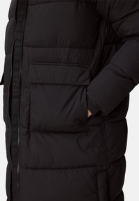 Black puffer jacket, quilted design with visible stitching, features zip closure, two side pockets, and ribbed wrist cuffs.