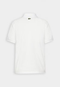 Camisa polo blanca de manga corta con cuello plano y un pequeño logo de Lacoste verde en la parte posterior. Hecha de una tela suave y ligera.