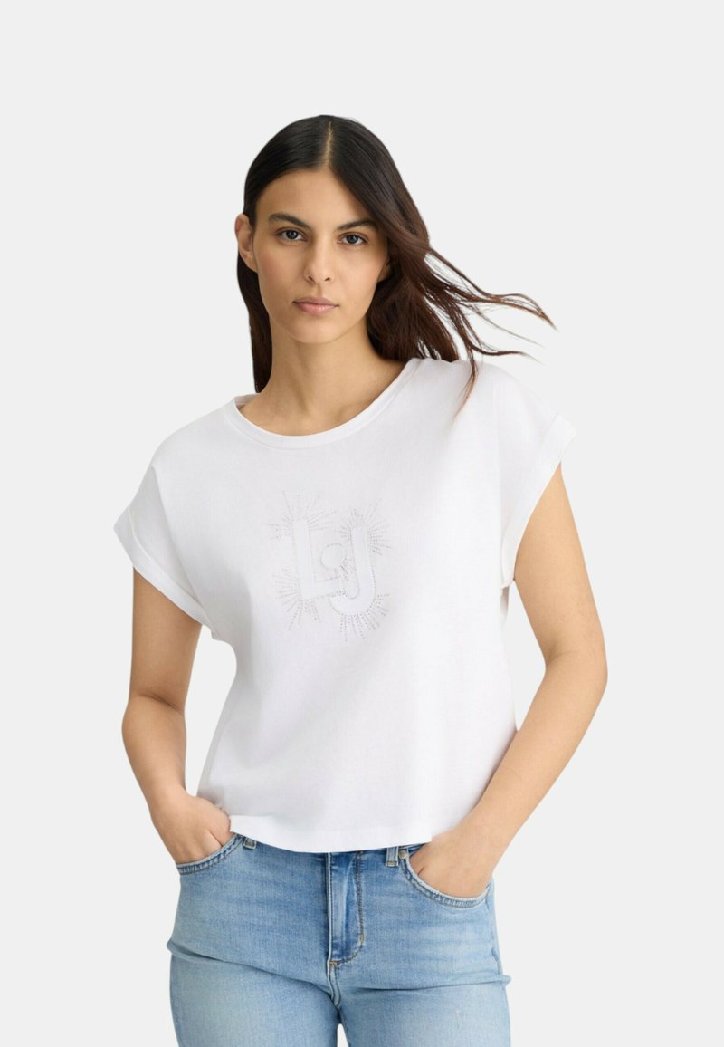 T-shirt blanc à manches courtes avec un col rond et un imprimé graphique discret au centre. Matière douce, design court, coupe décontractée.