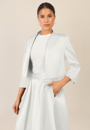 Giacca bianca corta con colletto arrotondato, maniche a tre quarti e design elegante, abbinata a una gonna a pieghe coordinata.