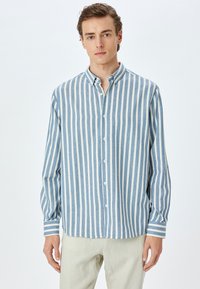 Blauw-wit gestreepte overhemd met lange mouwen en een knoopsluiting kraag; heeft verticale strepen en een relaxte pasvorm.