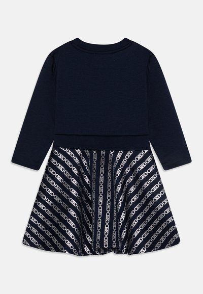 Robe marine à manches longues avec un haut ajusté et une jupe évasée. La jupe présente des motifs de chaînes argentées alternés sur un fond sombre.