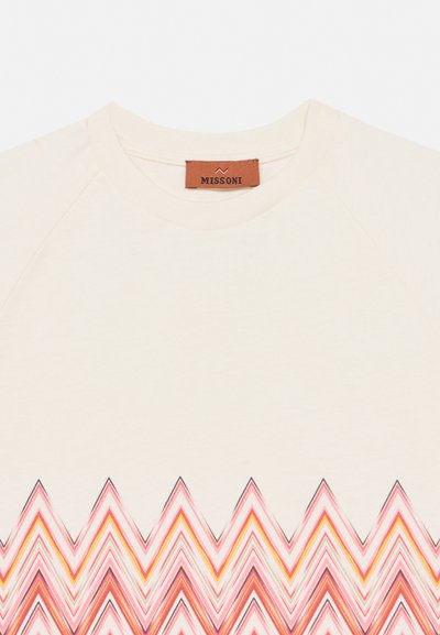 Τοπ σε κρεμ χρώμα με στρογγυλή λαιμόκοψη, με πολύχρωμο ζιγκ-ζαγκ σχέδιο κοντά στο κάτω μέρος και καφέ ετικέτα της μάρκας Missoni μέσα στο γιακά.
