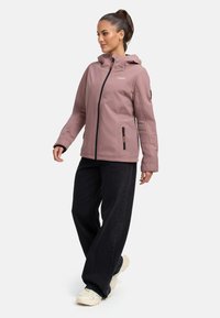 Light pink waterproof jacket with a hood, front zipper, and side pockets, paired with black wide-leg pants and chunky white sneakers.