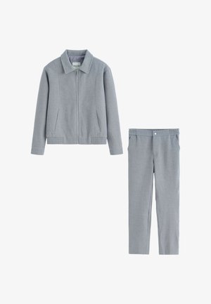 Veste zippée gris clair avec col et ceinture élastique, associée à un pantalon léger assorti avec un bouton avant et des poches.