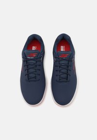 Navy athletic shoes with a textured upper, laced design, and red accents. Features a cushioned insole and a contrasting white outsole.