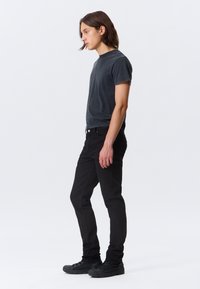 Black cotton t-shirt with short sleeves, paired with slim-fit black jeans and black sneakers. Simple, casual design without notable patterns.