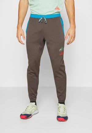Brązowe joggery z wiązaniem w pasie, bocznymi kieszeniami i turkusowymi akcentami. Posiadają detal z logo z przodu.