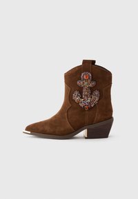 Brown suede ankle boot with low stacked heel, pointed toe, and colorful gemstone-embellished anchor design on the outer side.