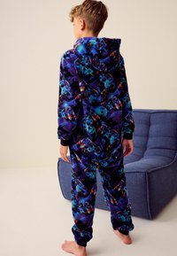 Bedrukte groene hoodie onesie van fleece met levendige patronen van gamecontrollers. Beschikt over mouwen en pijpen met boorden, een zachte textuur en een relaxte pasvorm.