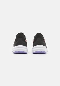 Des chaussures de sport noires avec une tige en mesh, une semelle intermédiaire blanche et une semelle extérieure violette. Elles présentent un design élégant et des accents roses contrastants au niveau du talon.