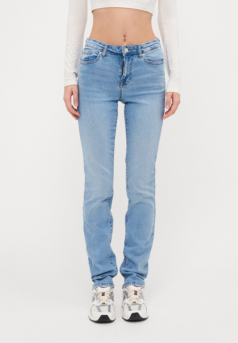 Jeans skinny de culoare albastru deschis, cu talie medie, realizate din denim, având cinci buzunare, închidere cu nasture și detalii discrete de uzură.
