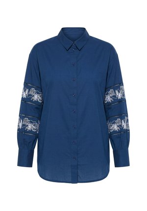 Blauwe blouse met lange mouwen, knopen en kraag, met witte bloemkantpanelen aan de boven- en ondermouwen.