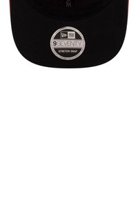 Czarna czapka baseballowa z wygiętym daszkiem, wykonana z materiału, z metalową etykietą z napisem "NEW ERA 9SEVENTY STRETCH-SNAP" z przodu.