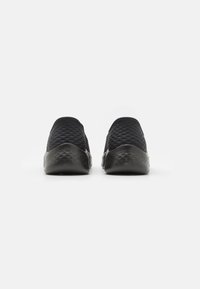 Black slip-on shoes with a quilted texture and smooth rubber sole. The design features a seamless upper and slightly rounded toe.