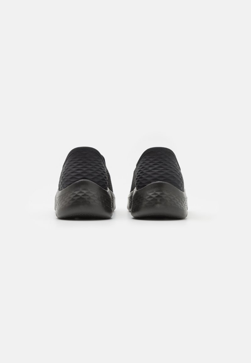 Scarpe slip-on nere con texture trapuntata e suola in gomma liscia. Il design presenta una tomaia senza cuciture e una punta leggermente arrotondata.
