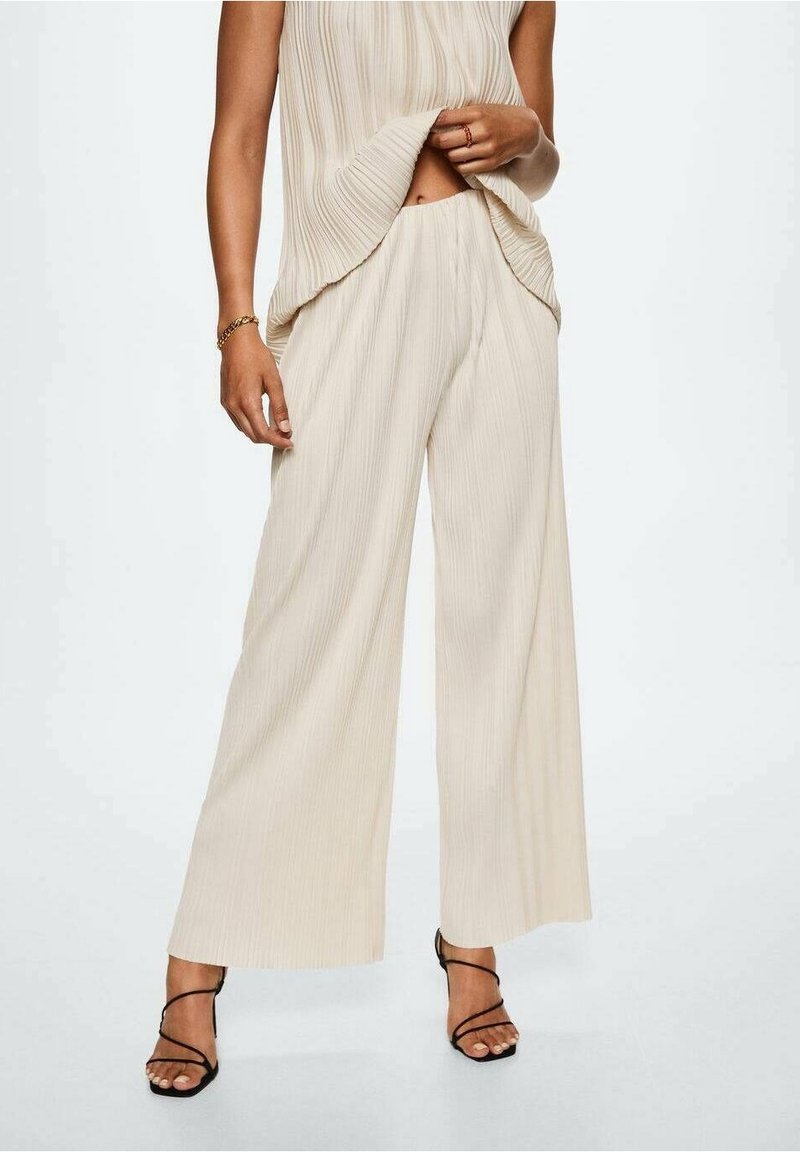 Béžové široké kalhoty s plisovaným designem a texturovaným povrchem. V setu se shodným topem, který zdobí jemné vertikální pruhy.