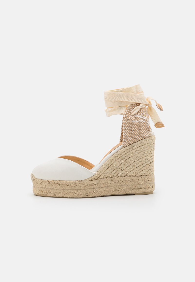 Sandalo con zeppa in espadrille bianco, suola in juta, lacci in tessuto alla caviglia e un accento in beige texturizzato sul tacco. Parte superiore liscia con design a punta arrotondata.