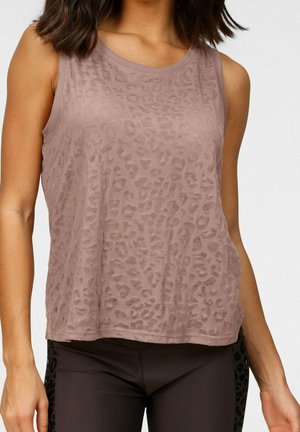 Woman wearing sleeveless mauve top with subtle leopard print and dark fitted leggings against plain background.