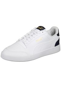 Białe skórzane trampki z teksturowanym noskiem, kontrastującym granatowym piętkiem i złotymi detalami logo po bokach i na języku. Płaskie sznurowadła.