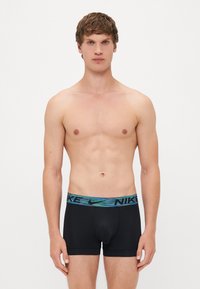 Zwarte boxershorts met een meerkleurige Nike tailleband. De stof lijkt soepel en rekbaar, ontworpen voor comfort en ondersteuning.