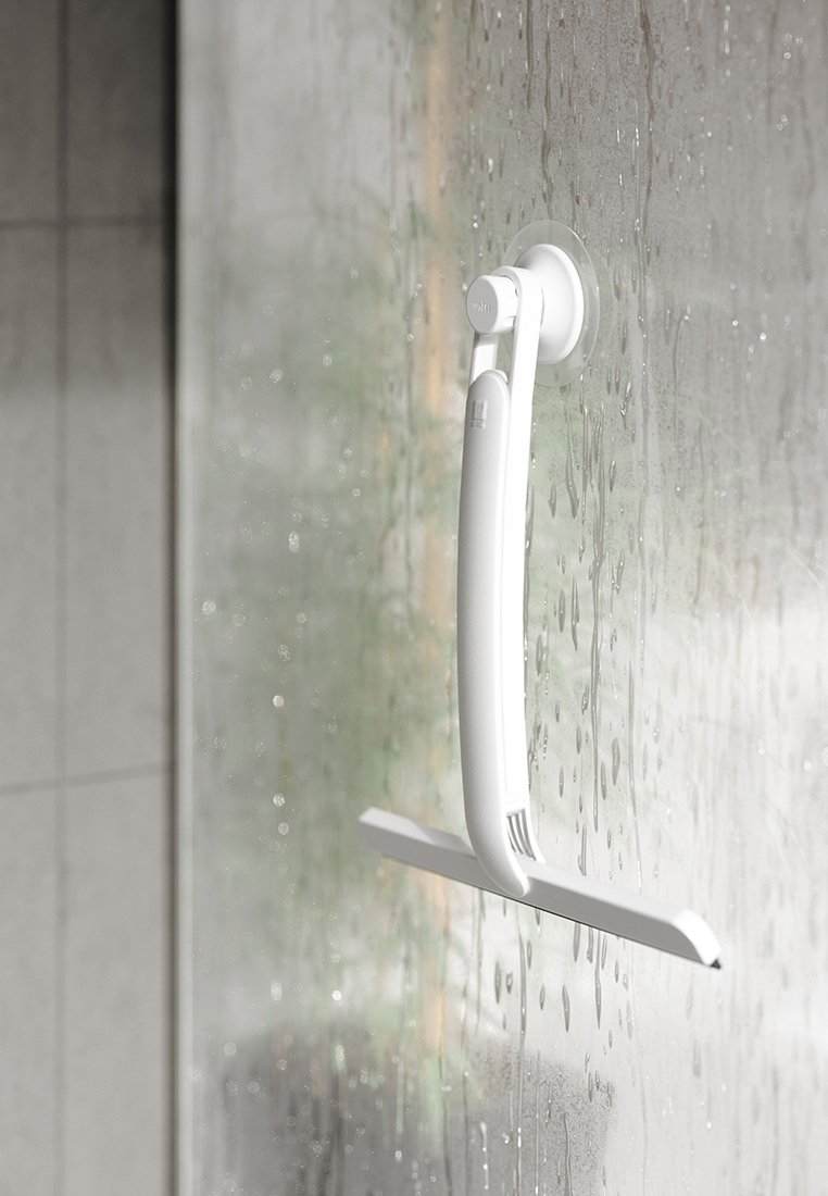 Weißer Abzieher mit Saugknopfgriff, der an einer nassen, dampfenden Glas-Duschkabine in einem gefliesten Badezimmer befestigt ist.