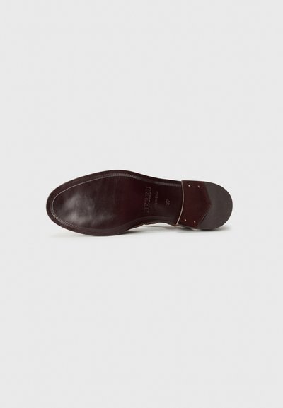 Brown leather shoe sole with a smooth finish, rounded shape, and a stitched edge. Features a hexagonal accent near the heel with metal details.
