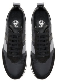 Schwarze und graue Sportsneaker mit einem strukturierten Obermaterial aus Stoff, Wildleder-Akzenten, gepolstertem Kragen und flachen Schnürsenkeln. Gummisohle mit weißem Rand.