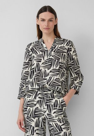 Zwart-witte blouse met patroon, met een V-hals, lange mouwen en een relaxte pasvorm, gecombineerd met een bijpassende broek met een vergelijkbaar ontwerp.