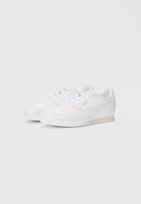 White athletic sneakers with light beige accents, smooth synthetic upper, lace-up front, textured rubber sole, and subtle branding on the side.