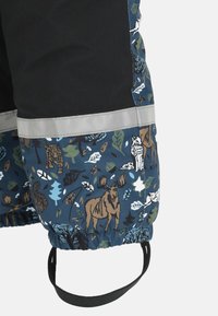 Waterdichte kinderbroeken met elastische manchetten, bedrukking van bosdieren, zwarte voetstrap en reflecterende strip op blauwe en zwarte stof.