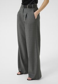 Pantalones de pata de elefante grises a cuadros con cintura alta, que cuentan con un cinturón negro y bolsillos. Tejido suave con un corte a medida y un elegante caída.