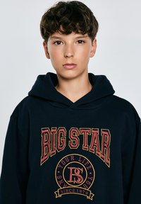 Sudadera azul marino con un gran gráfico "BIG STAR" en letras gruesas de color amarillo y rojo, con una textura suave y un bolsillo tipo canguro.